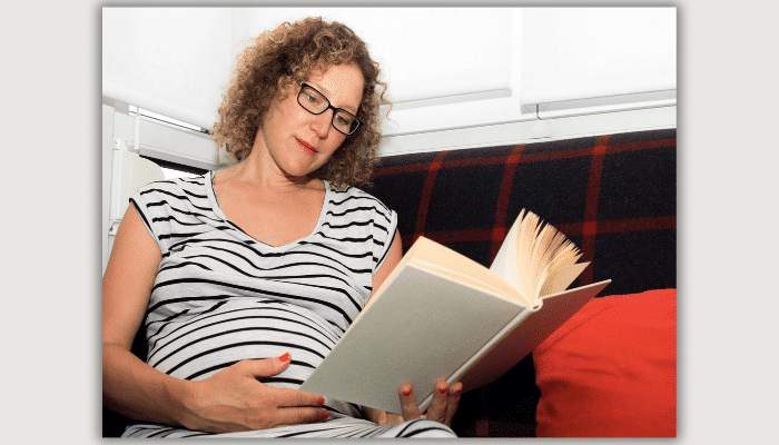 Pregnant woman wearing glasses reading a book